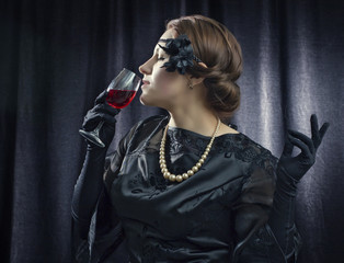 Fototapeta na wymiar Beautiful woman in a retro style with a glass of red wine.
