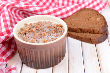 Boiled buckwheat with milk in bowl on table close-up