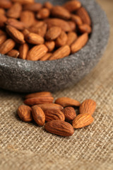 Almonds in bowl on sackcloth background