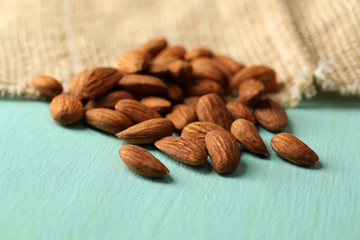 Almonds on color wooden table, on sackcloth background