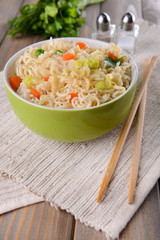 Tasty instant noodles with vegetables in bowl on table close-up