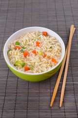 Tasty instant noodles with vegetables in bowl on table close-up