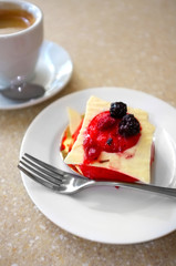 Tasty cake with berries and cup of coffee on table in cafe