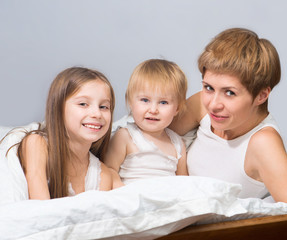 Mother with two children lying on bed