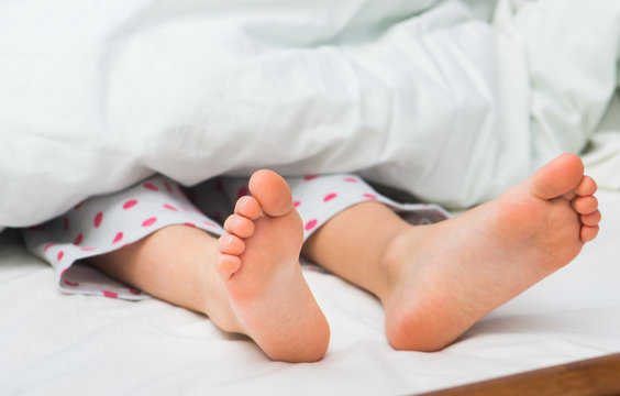 Young kid bare feet in bed