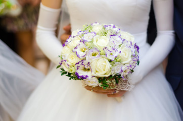 Wedding bouquet with many white roses in hands of bride