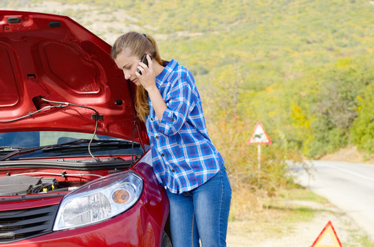 Young woman near broken car speaking by phone