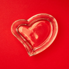 Heart made of glass on the red surface