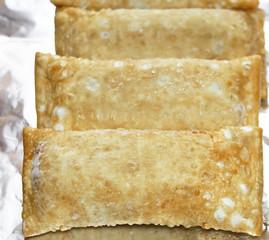 Frozen uncooked vegetarian egg rolls on aluminum foil