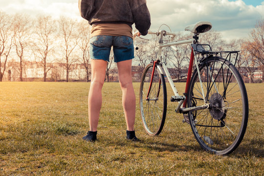 Young woman standing in park with bicycle