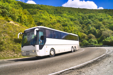 Tourist bus traveling on road among mountains - obrazy, fototapety, plakaty