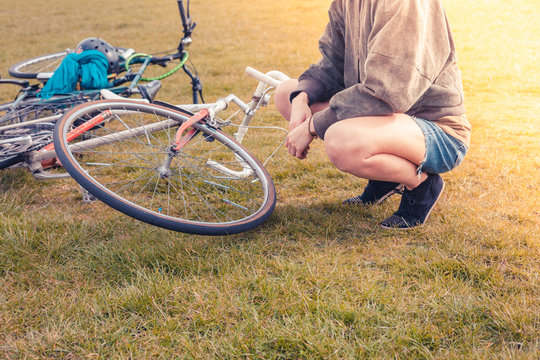 Young woman looking at her bicycle in park