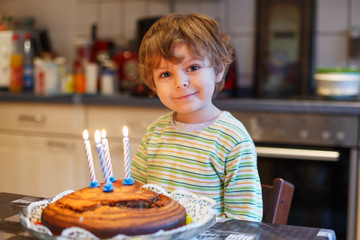 Adorable four year old boy celebrating his birthday and blowing