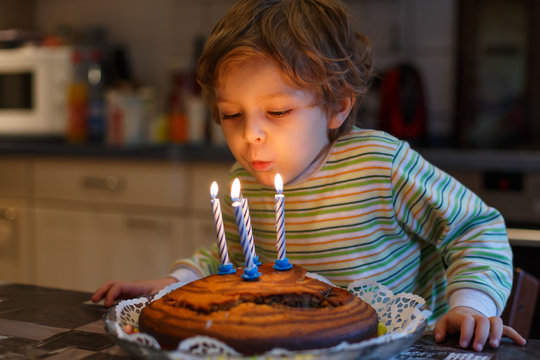 Adorable four year old boy celebrating his birthday and blowing