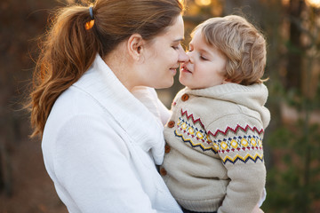 Young woman and little son hugging in evening light