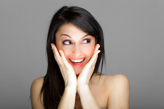 Beautiful surprised woman against a grey background