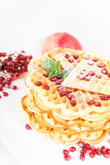 Crisp golden fresh baked waffle topped with strawberries on whit