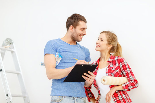 smiling couple with clipboard and wallpaper roll