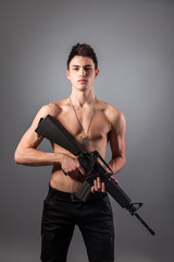 Fototapeta premium Handsome bare-chested soldier is holding a rifle