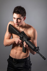 Handsome bare-chested soldier is holding a rifle