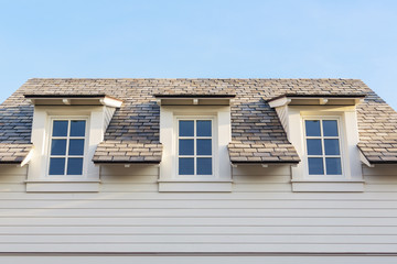 Upwards at 3 home attic windows with roof