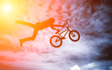 Man doing an jump with a bmx bike against sunshine sky.