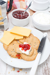 Breakfast with crackers, cheese, cream and berry jam, top view