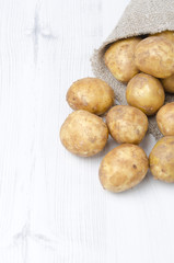 new potatoes in a sack on a white background, vertical