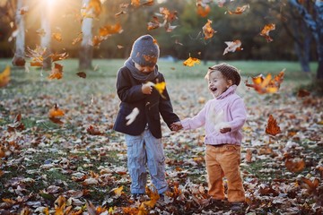 brother and sister playing in autumn park leaves