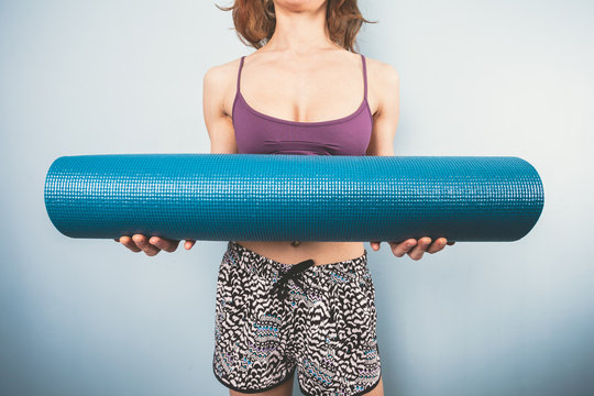 Athletic young woman holding a yoga mat