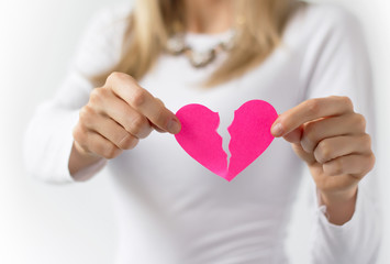 Woman symbolically tearing up pink paper heart