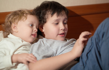 Two young children playing with a tablet