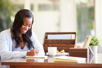 Woman Writing In Notebook Sitting At Desk - obrazy, fototapety, plakaty