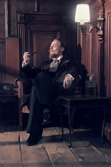 Vintage 1900 fashion man with beard and glasses. Sitting in old