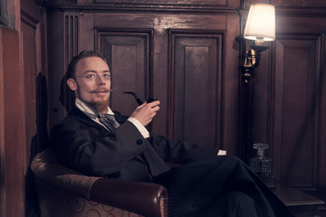 Vintage 1900 fashion man with beard and glasses. Sitting in old