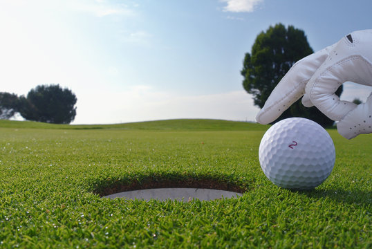 a man who push a ball in a golf hole