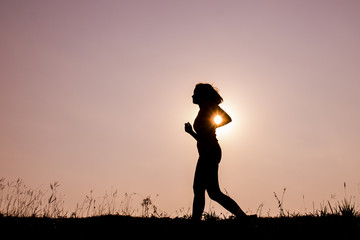 Silhouette young woman jogging with sunset