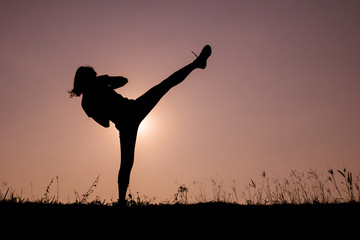 Silhouette of kick boxing girl exercising kick.