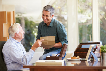 Senior Father Discussing Document With Adult Son