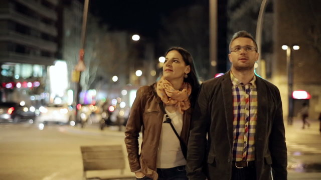 Young couple walking in night city, steadycam shot