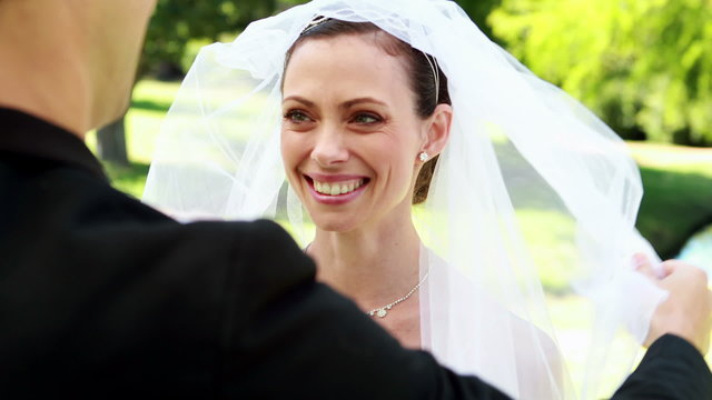 Groom lifting veil off beaming brides face