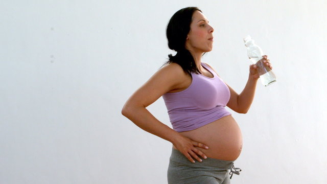 Pregnant brunette drinking water