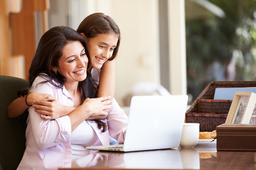 Mother And Teenage Daughter Looking At Laptop Together