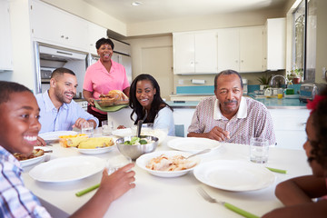Fototapeta na wymiar Multi-Generation Family Sitting Around Table Eating Meal