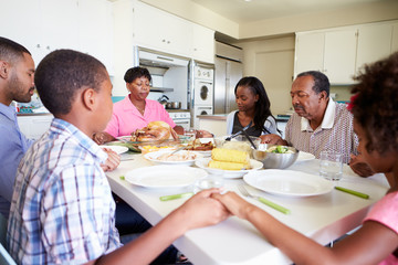 Fototapeta na wymiar Multi-Generation Family Saying Prayer Before Eating Meal