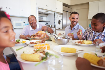 Obraz na płótnie Canvas Multi-Generation Family Sitting Around Table Eating Meal