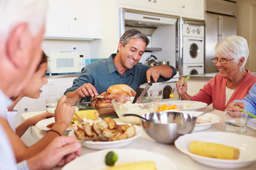 Obraz na płótnie Canvas Multi-Generation Family Sitting Around Table Eating Meal