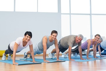 Obraz premium Group doing push ups in row at yoga class