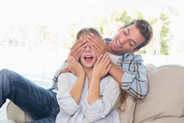 Man covering happy womans eyes in living room