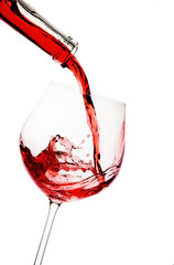 Red wine poured in a glass isolated on white